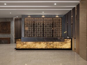 A reception area with a marble counter, a decorative screen, and a patterned floor. - Hotel Santika Batam (Batam)