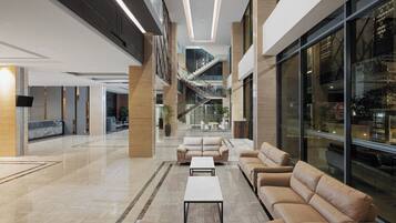 A spacious lobby with a central seating area, a staircase, and large windows.