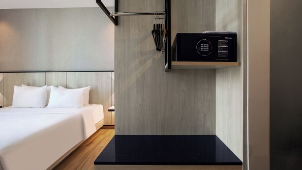 A hotel room with a bed, a black countertop, a microwave, and a wall-mounted towel rack. - Hotel Santika Batam (Batam)