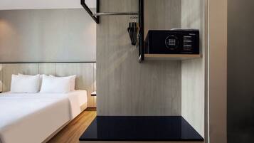 A hotel room with a bed, a black countertop, a microwave, and a wall-mounted towel rack.
