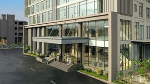 A modern building with a glass facade, a covered entrance, and a staircase leading to the entrance. - Hotel Santika Batam (Batam)