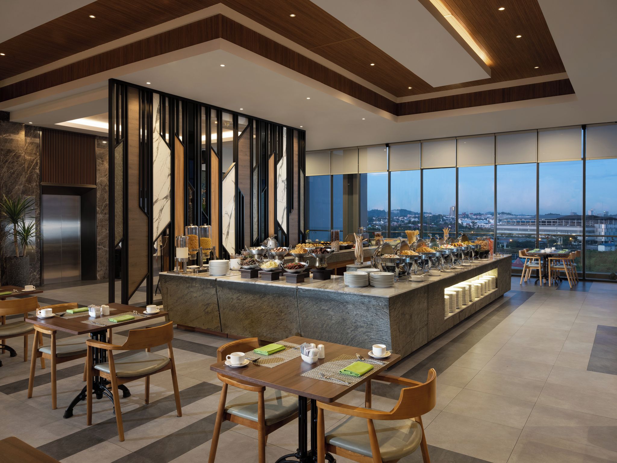 A modern dining area with a buffet, wooden chairs, and a view of the cityscape through large windows.