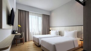 A hotel room with two beds, a desk, a chair, a TV, and a large window with curtains. - Hotel Santika Batam (Batam)