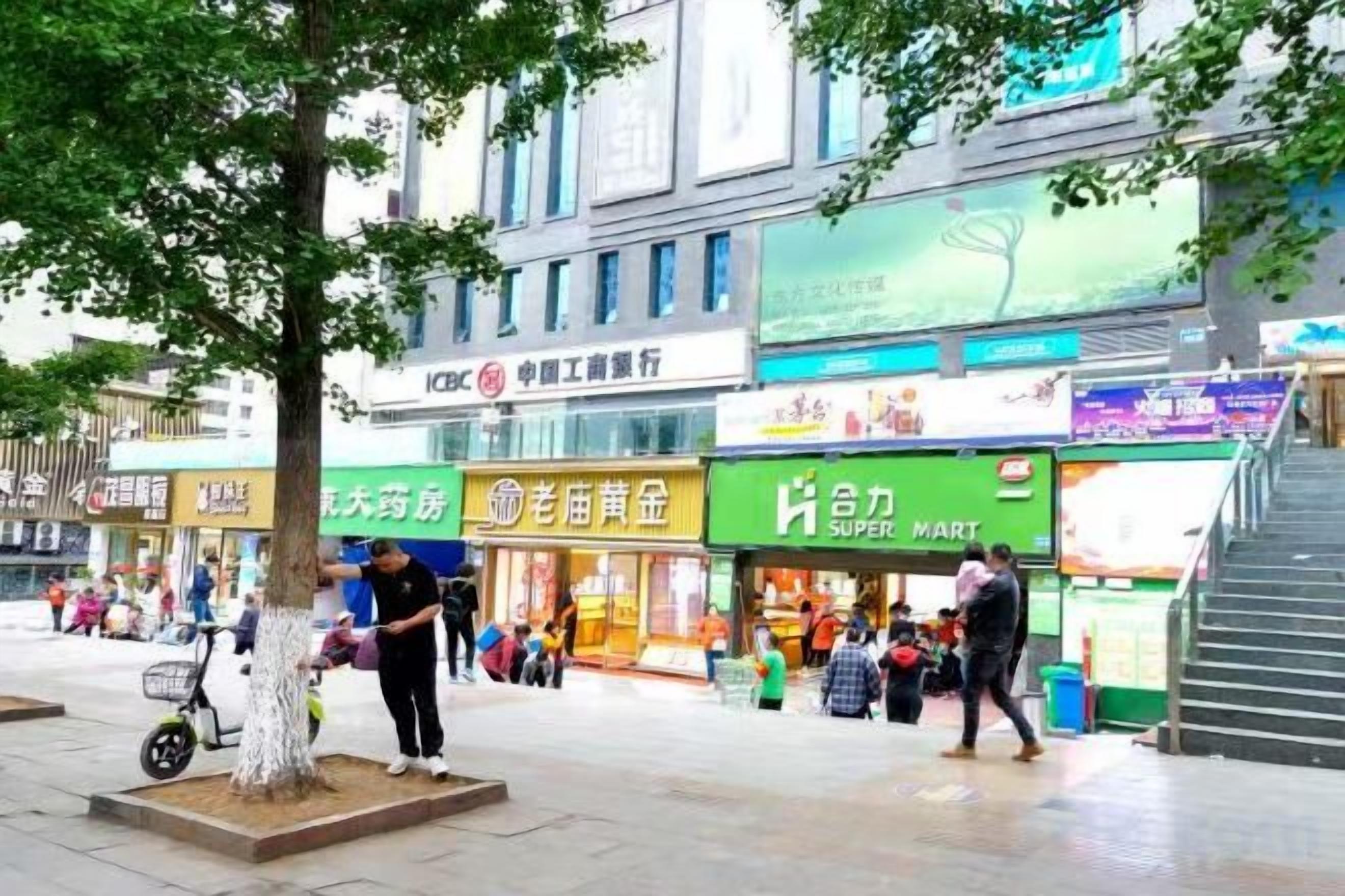 Eine Fußgängerzone mit Geschäften, darunter ein Supermarkt und eine Bank.