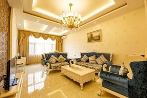 A living room with two sofas, a coffee table, a TV, and a chandelier.