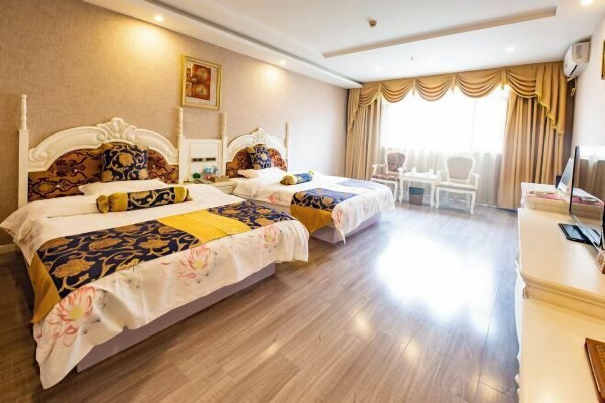 A hotel room with two beds, a desk, and a chair.