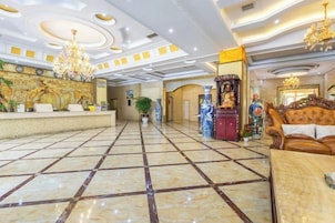Un vestíbulo de hotel con mostrador de recepción, candelabros y un altar decorativo.