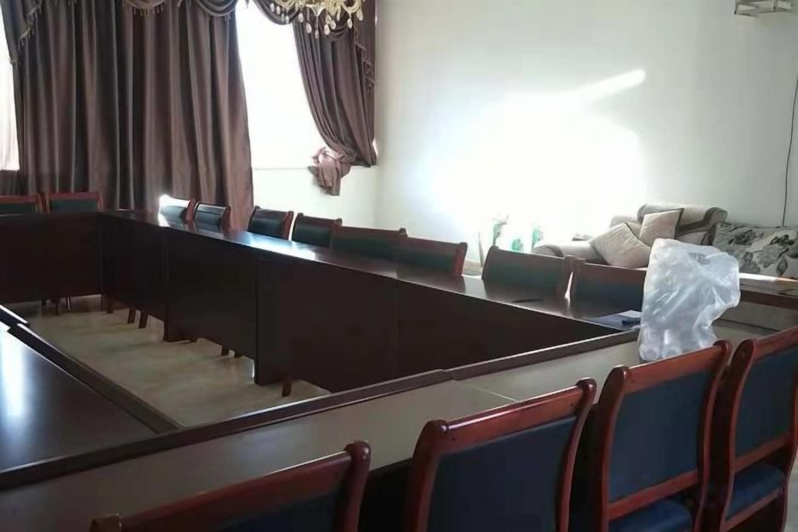 A conference room with a long table and chairs, a sofa, and a decorative wall piece.