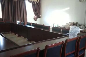 Une salle de conférence avec une longue table et des chaises, un canapé et un élément décoratif mural.