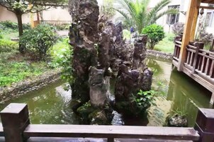 Una fuente de agua con una estructura rocosa en un jardín.
