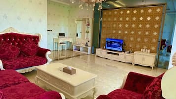 A living room with a red sofa, a white coffee table, and a television.