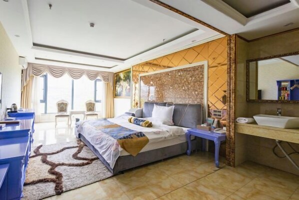 A modern bedroom with a large bed, a bedside table, a vanity with a mirror, and a view of the outdoors through a window.