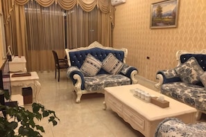 A living room with two patterned sofas, a coffee table, and a chair. - Paulolia Holiday Hotel (Panzhou)