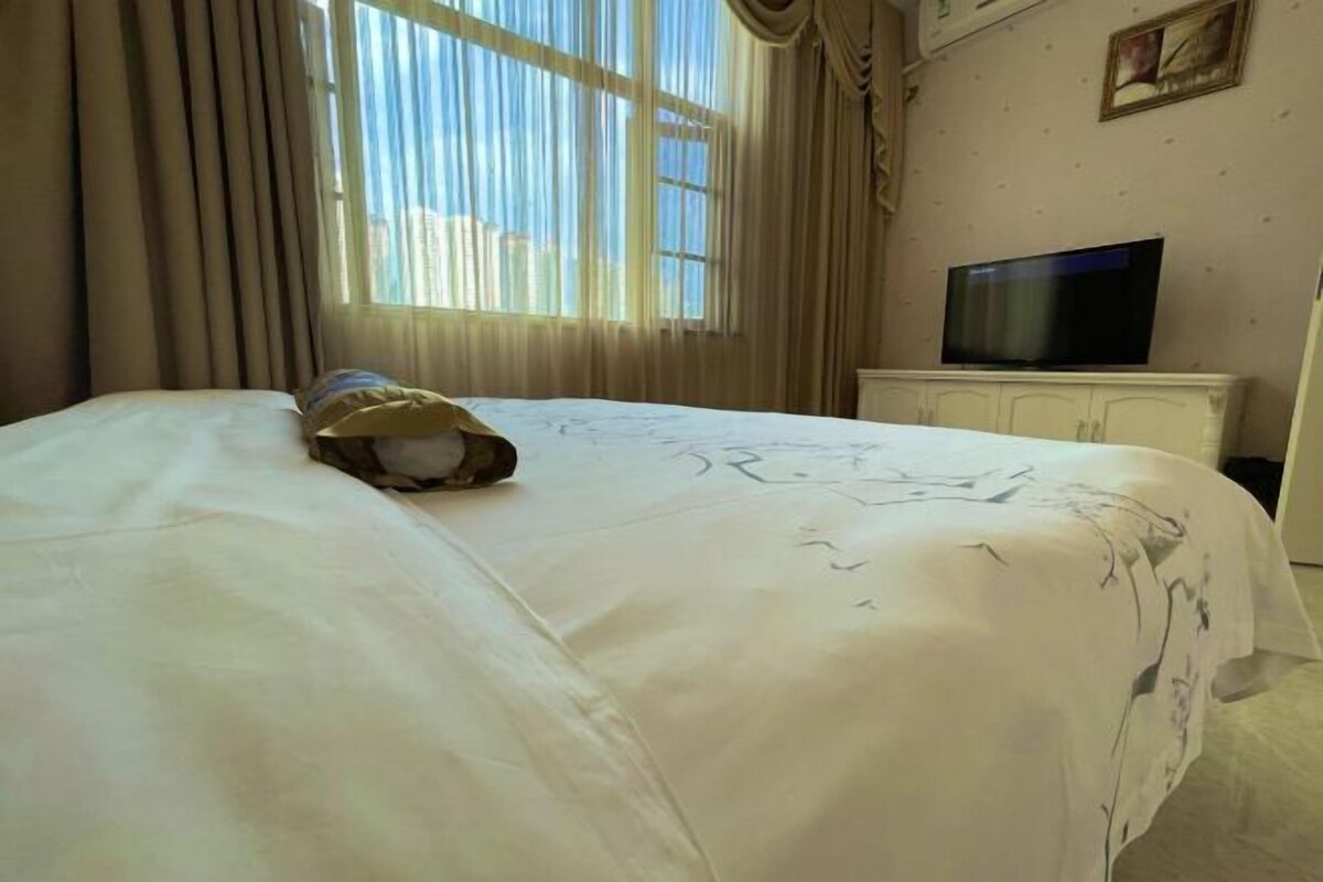 A hotel room with a bed, curtains, a television, and a cabinet.