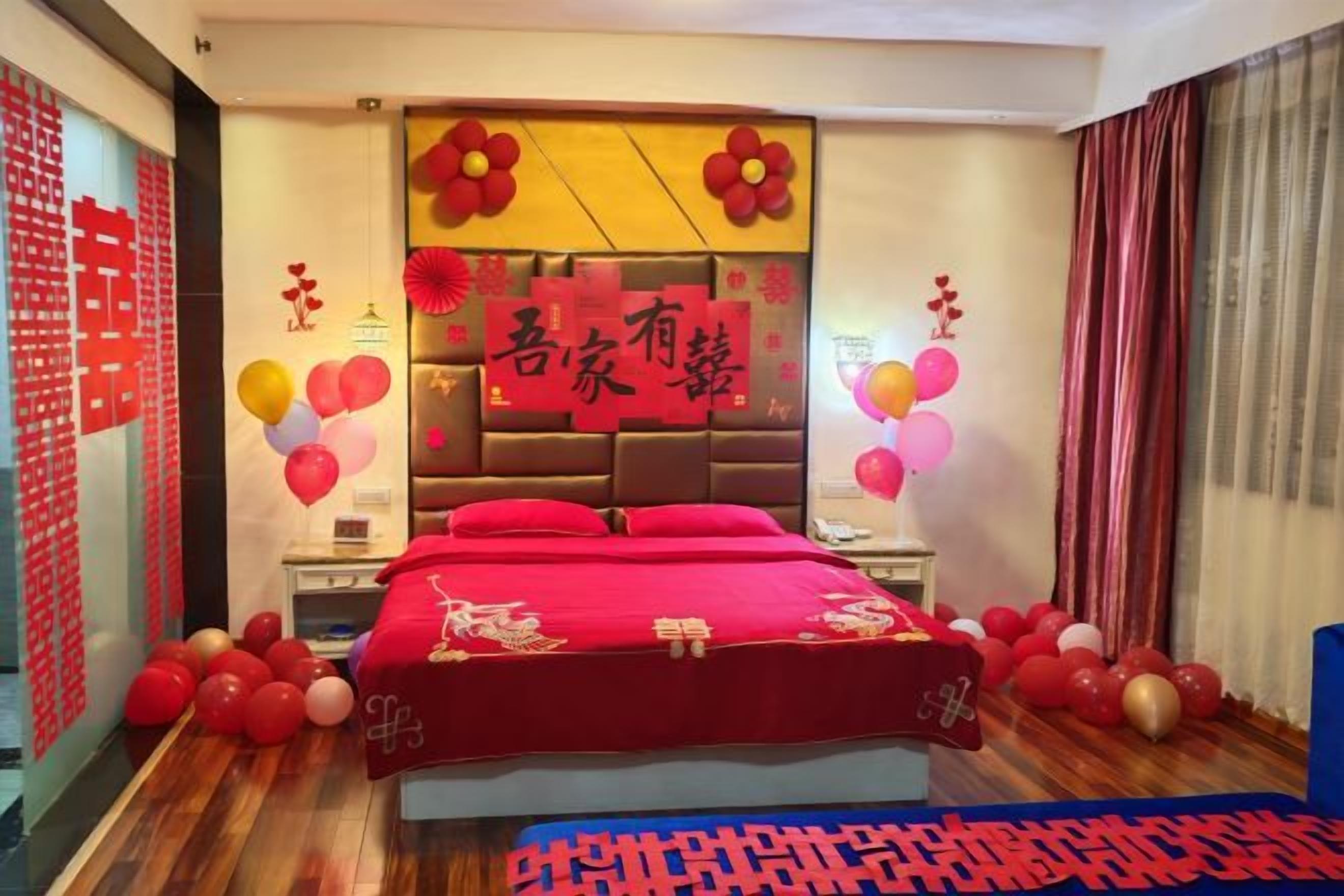 A bedroom with a large bed, a nightstand, a wall-mounted TV, and a decorative headboard.