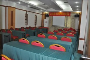 A conference room with rows of tables and chairs, a projector screen, and a banner on the wall. - Laibin Hotel (Laibin)