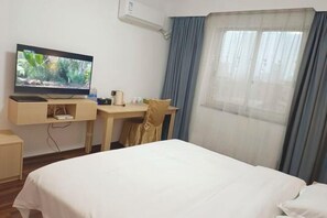 A hotel room with a bed, a desk with a computer, a TV, and a window with curtains. - Laibin Hotel (Laibin)