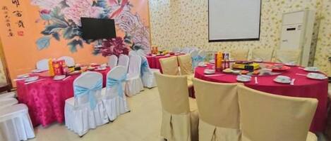 A conference room with round tables, chairs, and a projector screen.
