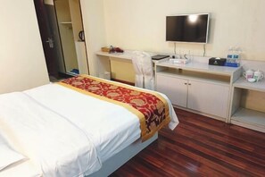 A hotel room with a bed, a desk, a chair, a television, and a wardrobe. - Laibin Hotel (Laibin)
