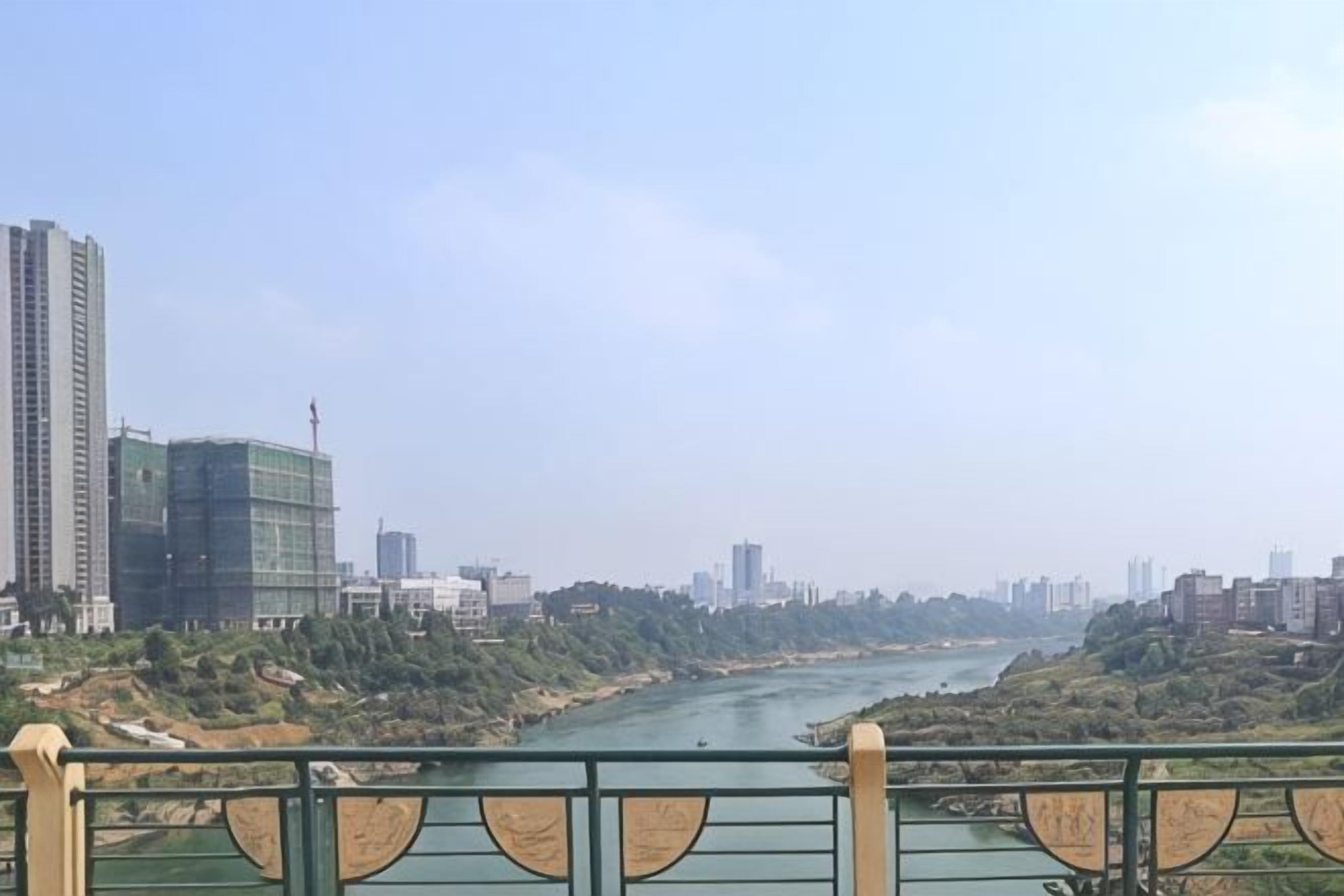 A river with a bridge in the foreground and a cityscape in the background.