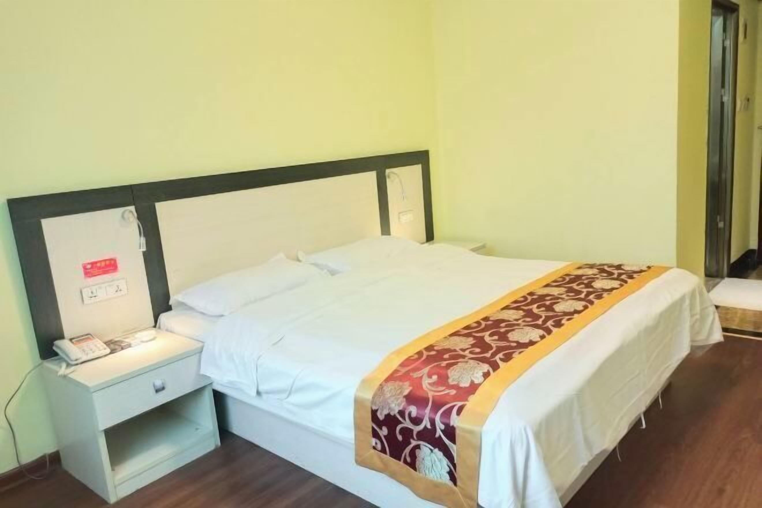 Una habitación de hotel con una cama, mesita de noche y teléfono.