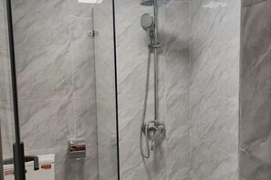 A glass-enclosed shower with a handheld showerhead and a wall-mounted faucet. - Laibin Hotel (Laibin)