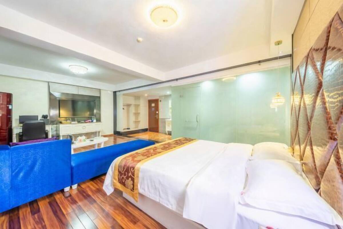 A hotel room with a bed, a desk, a chair, a mirror, and a wardrobe.