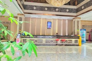 A hotel reception area with a marble floor, a reception desk, and a large chandelier. - Laibin Hotel (Laibin)