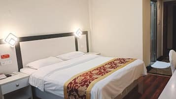 A hotel room with a single bed, a nightstand with a phone, and two wall-mounted lights.
