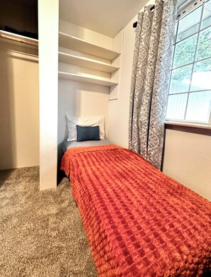 A bedroom with a bed, a window with curtains, a staircase, and a closet. - HOT TUB! Firepit - Bright Open-Near Airport & Freeway (Medford)