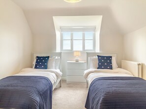 Une chambre avec deux lits, une table de chevet, une lampe et une fenêtre.