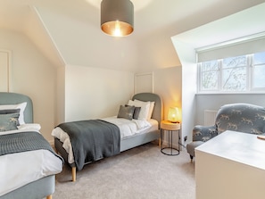 A bedroom with a bed, a chair, a lamp, and a window.