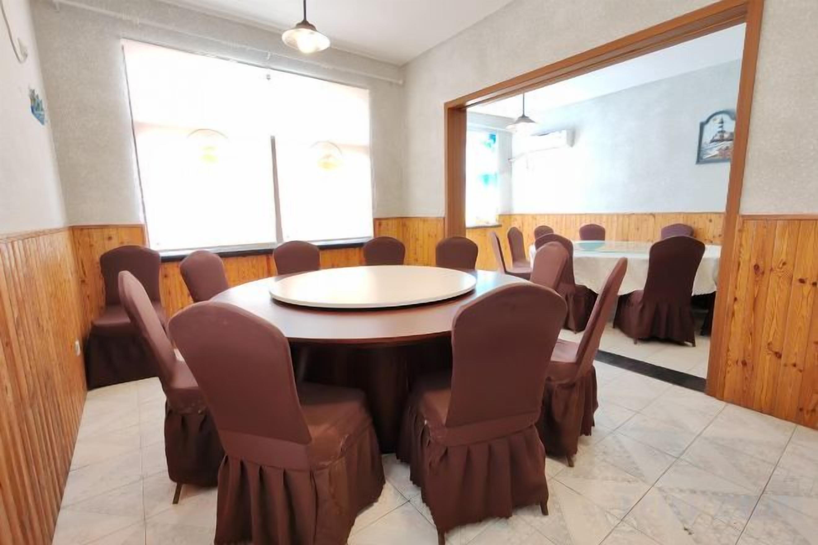 A conference room with a round table and chairs, large windows, and wooden paneling.