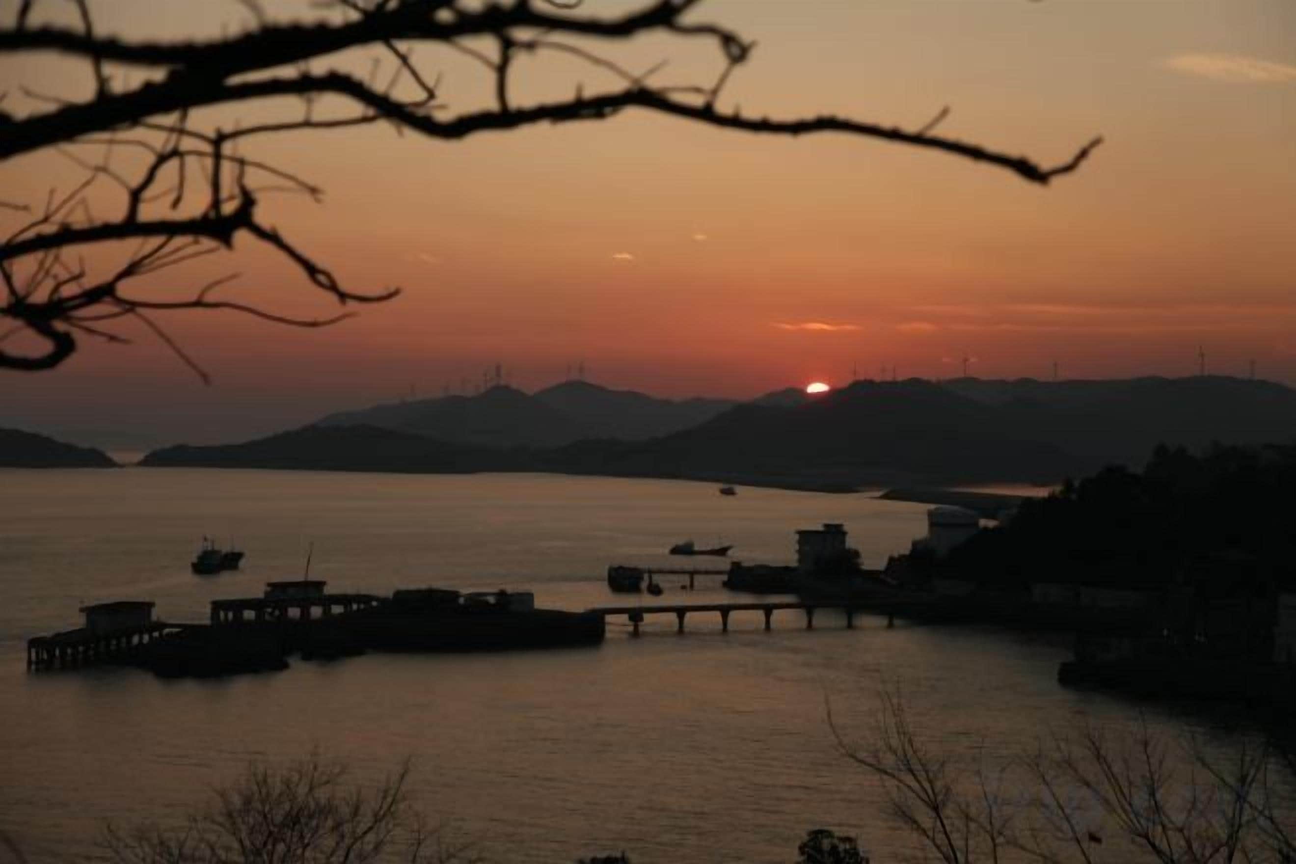 A sunset over a body of water with boats and a pier.