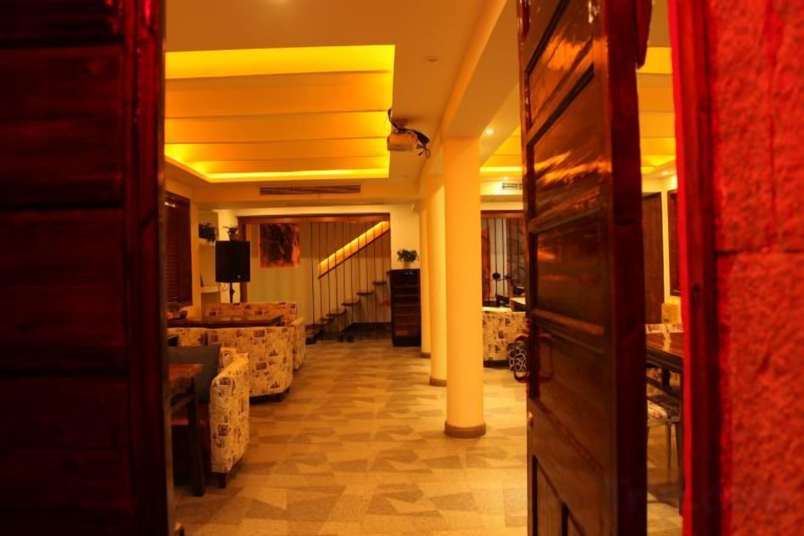 A hotel corridor with patterned flooring, a staircase, and a seating area with patterned furniture.