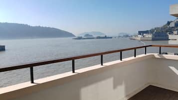 Un balcón con vistas a un río, un puente y colinas a lo lejos.