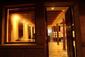 A corridor with wooden beams and a stone wall, leading to a room with a large window and a bed. - Tinghai Guesthouse (Yuhuan)