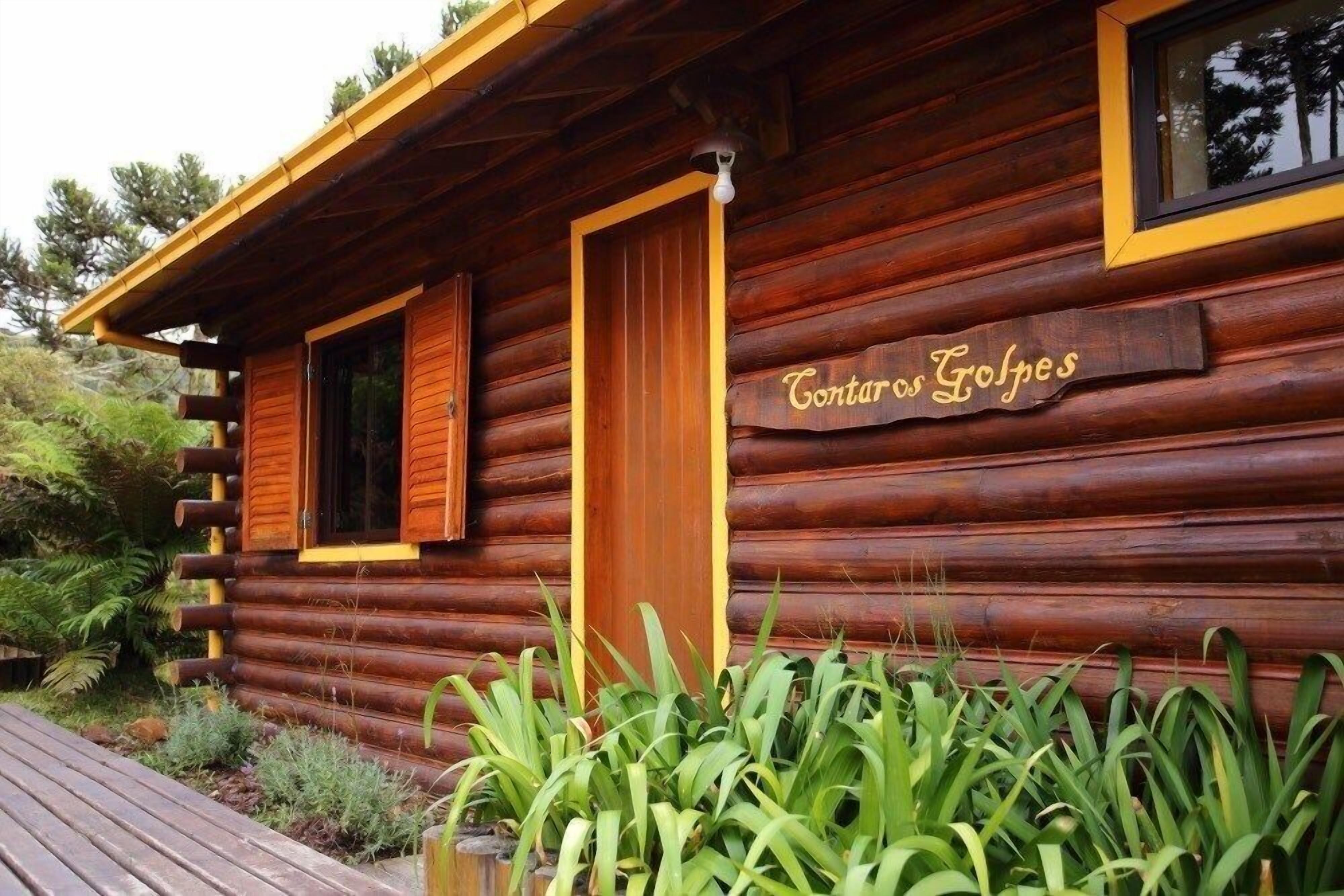 A log cabin with a wooden door and a sign that reads "Contaros Golpes".