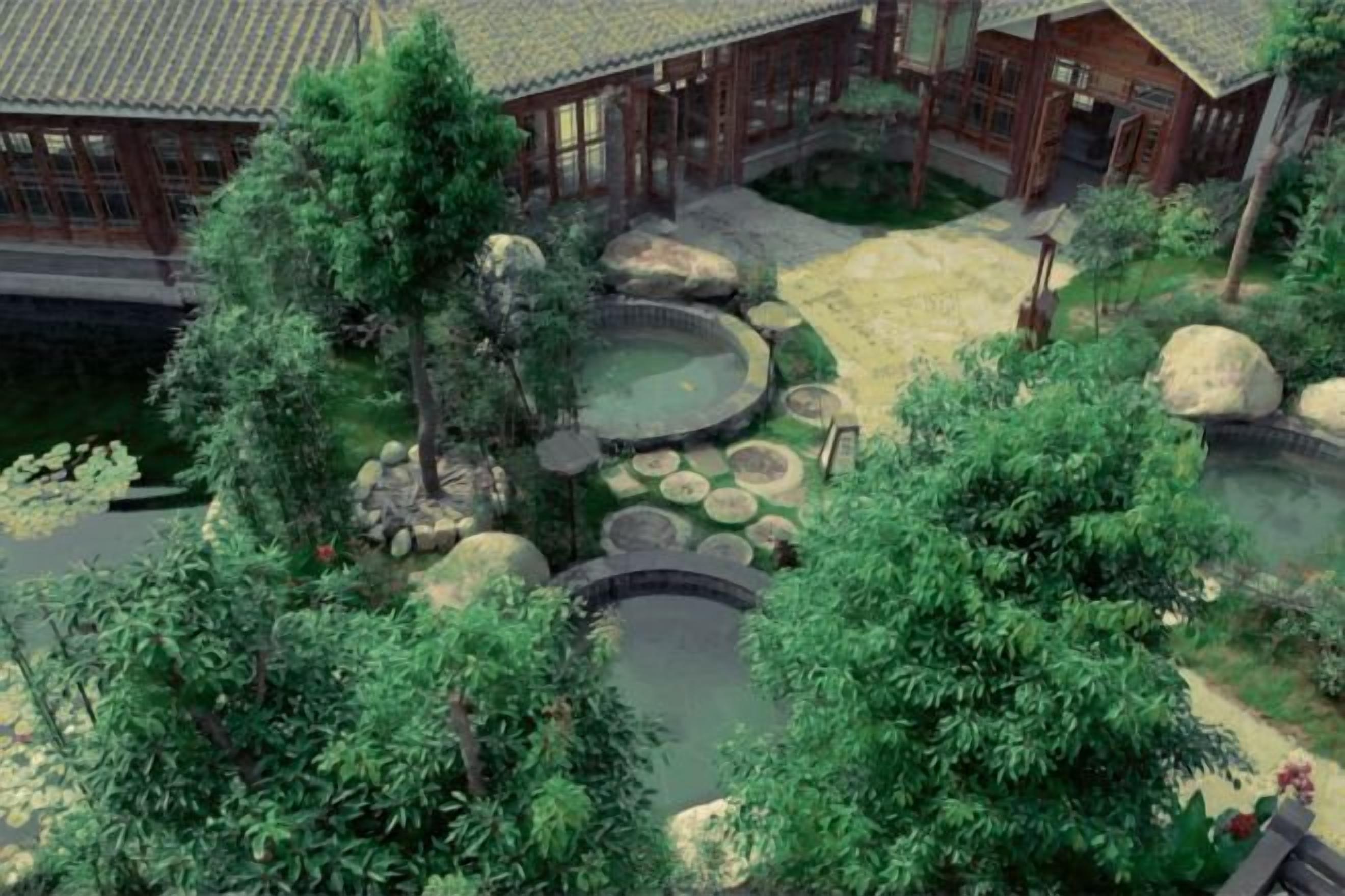 A traditional Japanese-style garden with a koi pond, stone lanterns, and a wooden building with a tiled roof.