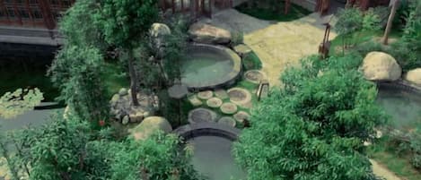 A traditional Japanese-style garden with a koi pond, stone lanterns, and a wooden building with a tiled roof.
