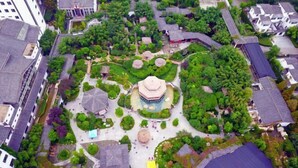 Vista aérea de un patio tradicional con una pagoda central, rodeado de abundante vegetación y edificios tradicionales.
