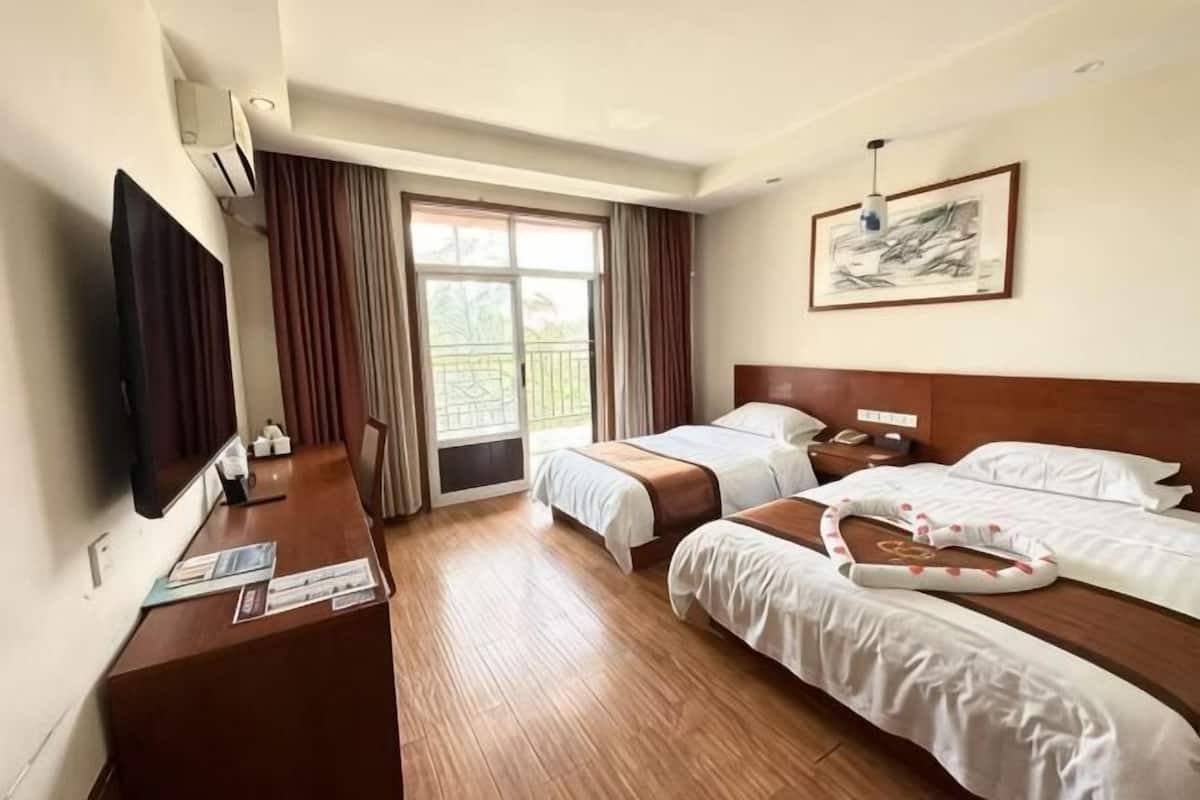 A hotel room with two beds, a desk, a TV, and a window with curtains.