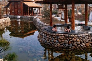 A hot spring area with a stone platform and a wooden pavilion. - Guantang Hot Spring (International) Resort (Linyi)