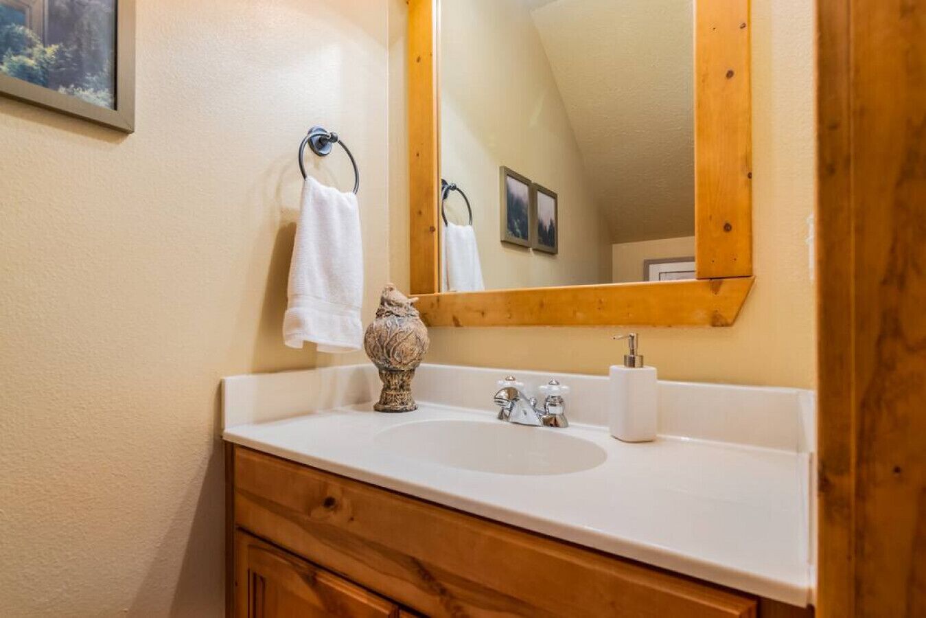Une salle de bain avec un lavabo blanc, un meuble-lavabo en bois et un miroir avec un cadre en bois.