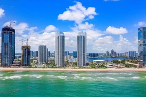A coastal cityscape with high-rise buildings, a beach, and a body of water.