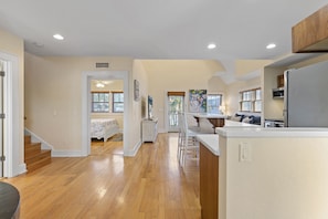 A spacious kitchen with wooden flooring, a dining area, and a living room with a sofa.