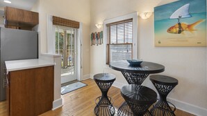 A kitchen with wooden cabinets, a refrigerator, and a dining area with three black metal stools and a table.
