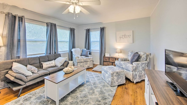 A modern living room with a sofa, two patterned armchairs, a coffee table, a TV, and a ceiling fan. - Longview Vacation Rental Home: 4 Mi to Dtwn (Longview)