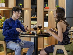 Un coin repas avec une table dressée pour deux personnes, comprenant un repas et des verres à vin.
