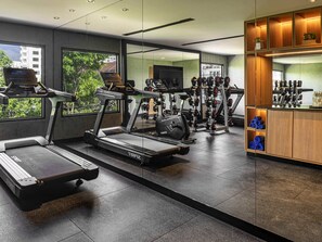 Un gimnasio moderno con cintas de correr, máquinas de pesas y una zona de bar.